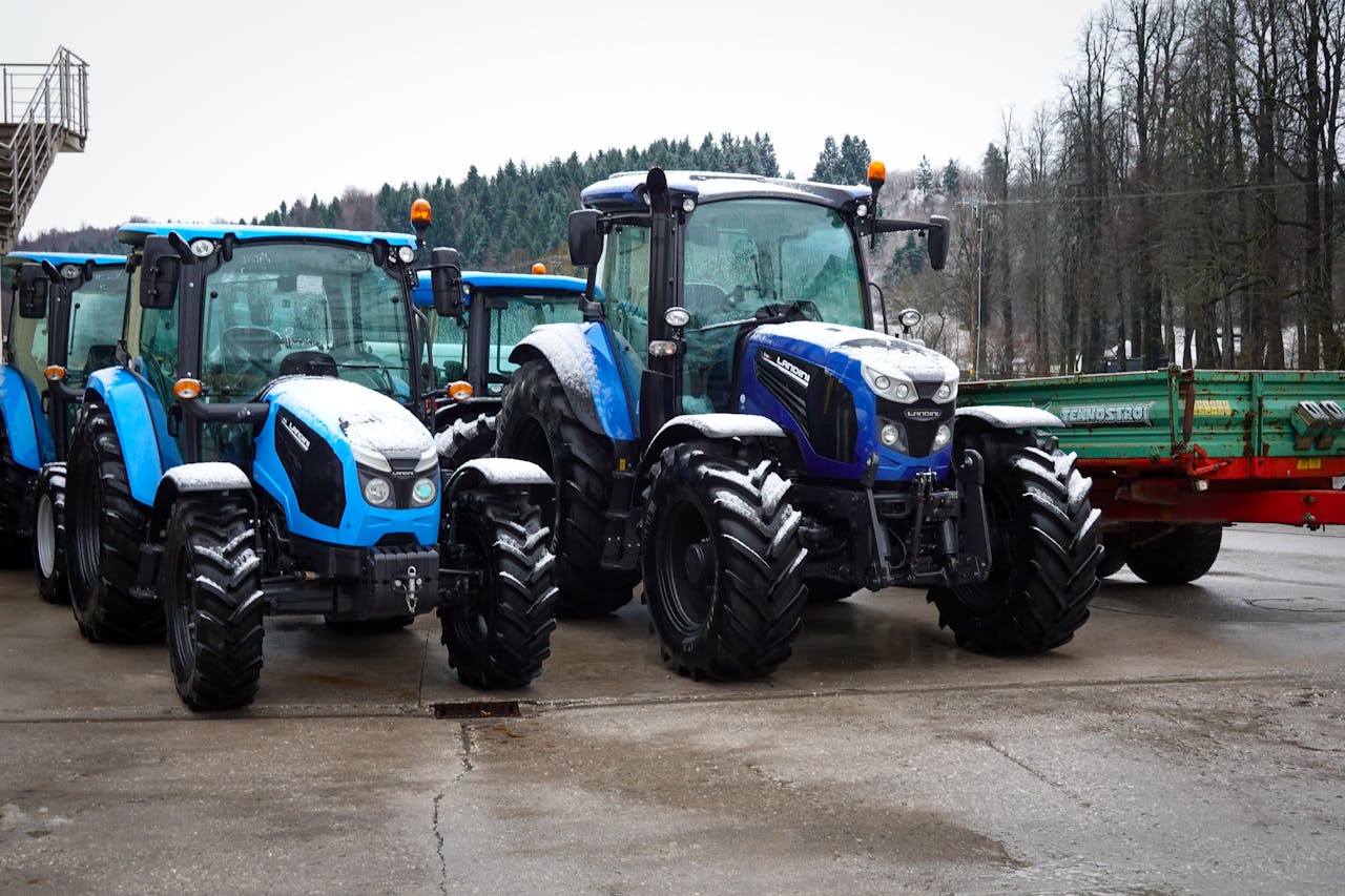 Line of blue tractors parked on a farm during winter.